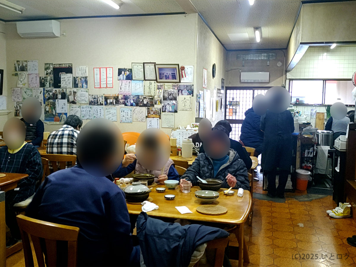 平日昼の橋本食堂 高知 須崎店内。壁一面のサインと写真に囲まれ、鍋焼きラーメンを楽しむ地元客で満席の様子。