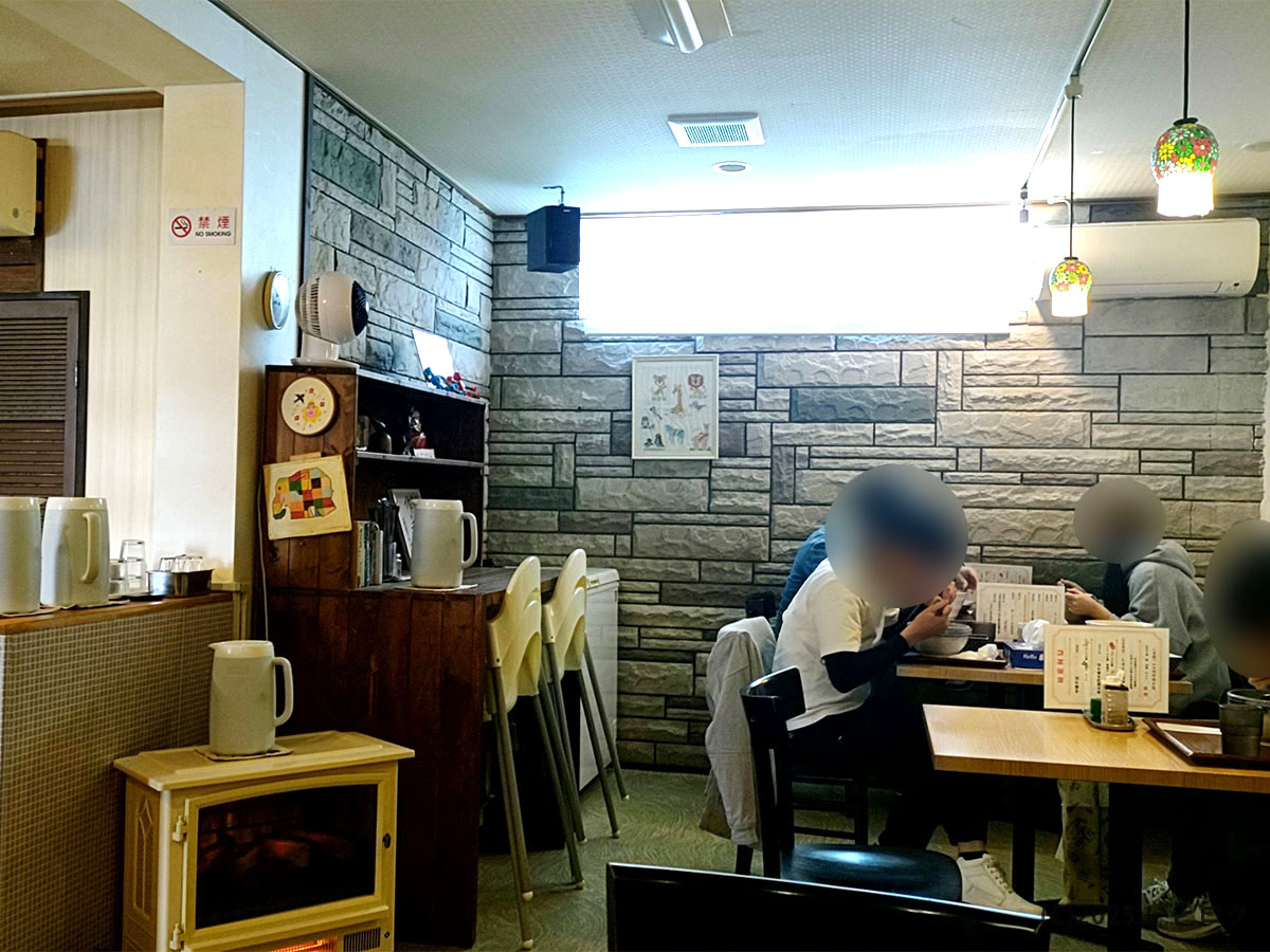 石壁風の壁とステンドグラス調ペンダントが映える店内。兵庫県太子町の「麦右衛門 太子」本店で、客たちが中華そばをすすっている落ち着いた雰囲気。