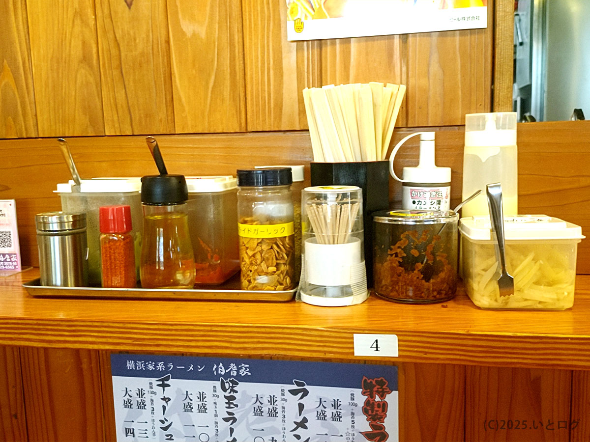伯耆家のカウンターに並ぶ卓上調味料。刻み生姜やフライドガーリック、豆板醤が揃い、店主のこだわりを感じさせる。