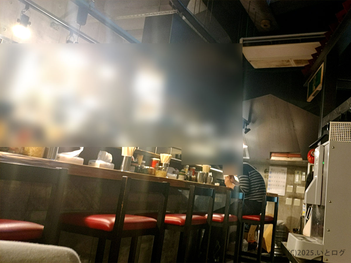 相模大野の家系ラーメン クックらの店内。赤い椅子が並ぶカウンター席で、コンクリ打ちっぱなしの落ち着いた雰囲気が広がる。