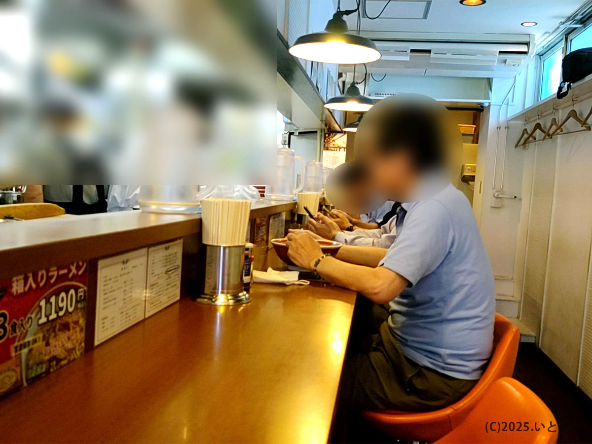 仙台の人気ラーメン店「中華そば 嘉一 国分町店」のカウンター席。落ち着いた照明の下で、常連客が嘉一の中華そばを味わっている様子。嘉一(かいち)の本店と同じく、丁寧な接客と活気ある厨房が印象的。