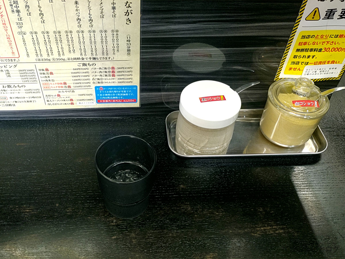 みずさわ屋のカウンター席。卓上には白コショウとコショウの瓶、メニュー表が整然と並ぶ。仙台・愛子エリアで人気の中華そば店らしい落ち着いた雰囲気。