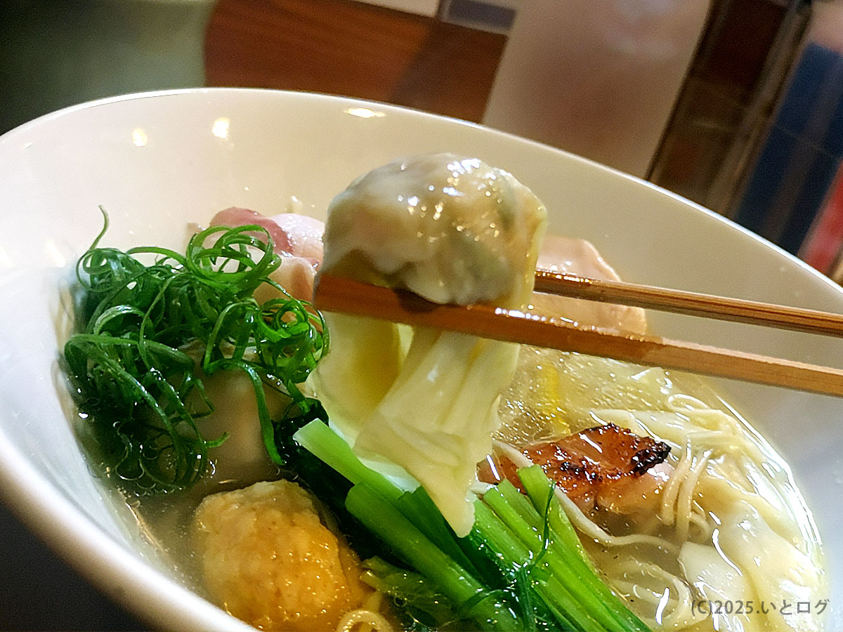 甲府の鶏そばAkariにて、ワンタンを箸で持ち上げた瞬間。鶏ベースの優しい白湯スープが絡み、具材の風味が立つ。山梨ラーメンの中でも人気店として口コミの多い店の一皿。