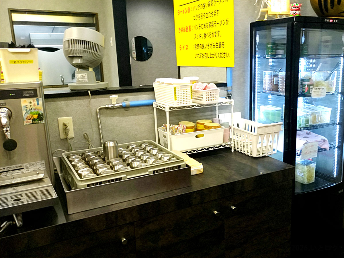 との丸家 伊勢崎店の店内セルフコーナー。家系ラーメンに合うライスや調味料が並ぶ様子