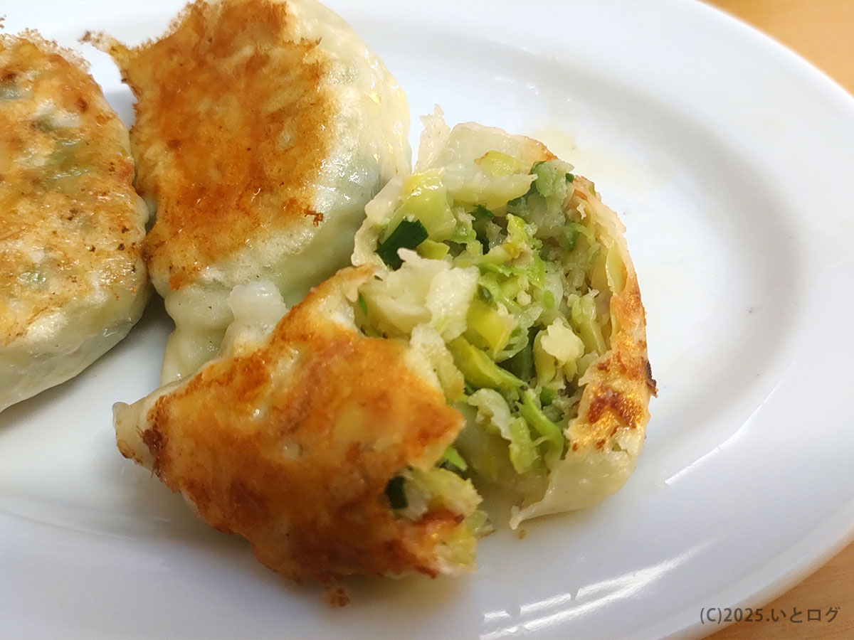 野菜ぎっしりの〈らーめん大金 餃子〉を半分に割った断面。香ばしい焼き目と瑞々しい緑野菜が食欲をそそる