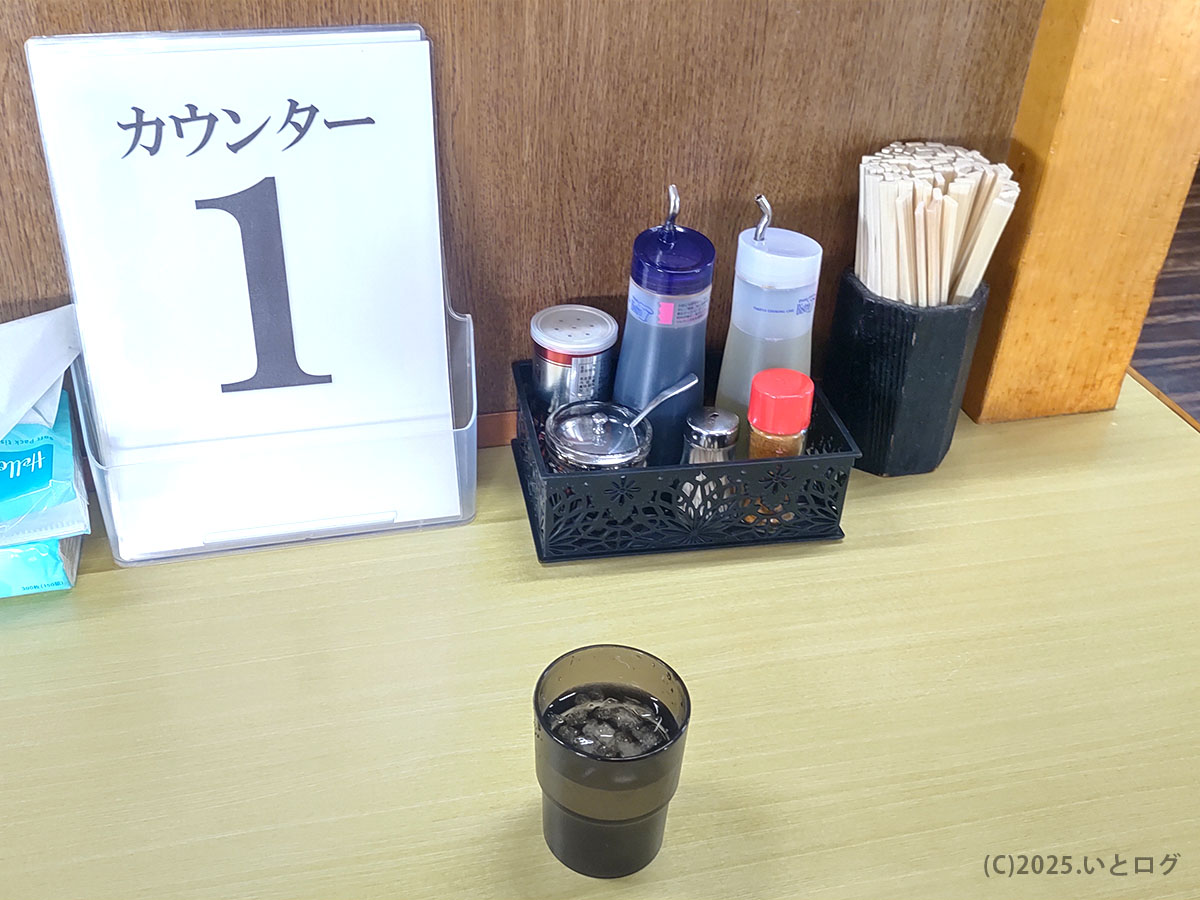 『麺屋ようすけ 本店』カウンター1番席。割り箸や調味料が整列し、事故物件の噂とは無縁の清潔感を感じる店内ショット。