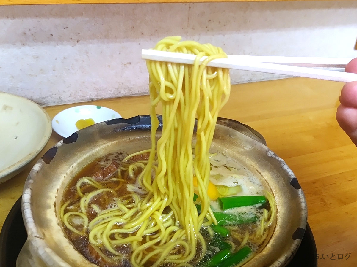 グツグツ煮立つ土鍋から麺をリフトアップ。熱気まで伝わる「鍋焼きラーメン まゆみの店」の名物ショット。