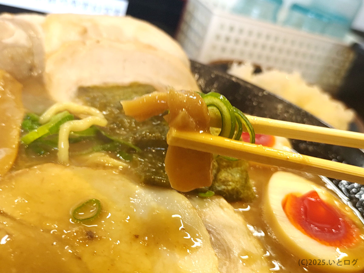 らーめん与七 堅田店の名物「豚そば」をアップで写したもの。濃厚な豚骨魚介スープにメンマと青ねぎが浮かび、箸で持ち上げると奥には半熟味玉や大ぶりチャーシューが見える。