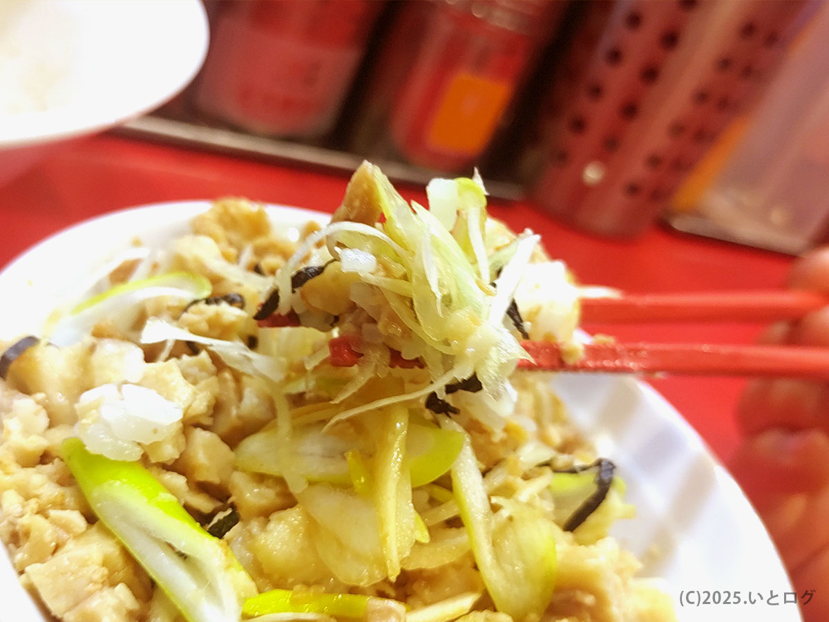 東京麺珍亭本舗 甲府南店メニューの角切りチャーシュー&白髪ネギを赤箸でリフト。油そばの食感を盛り上げる人気トッピング。