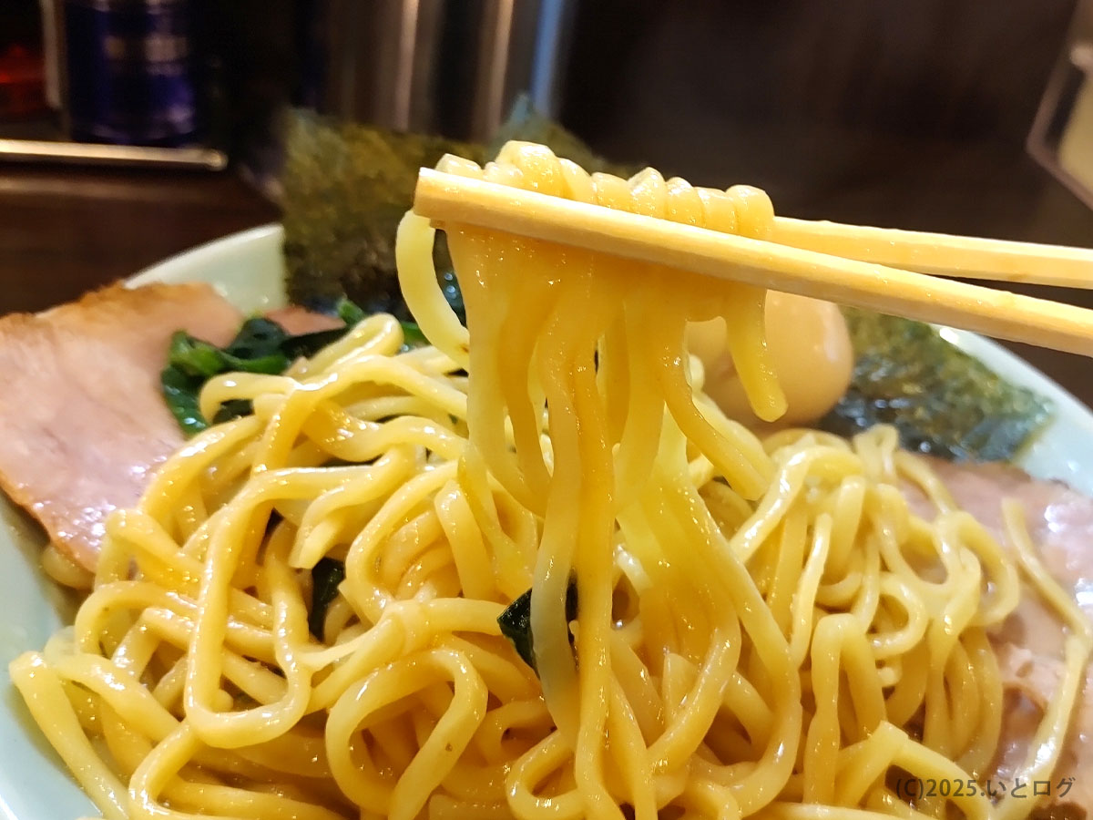 「雷家 山梨」中太麺を箸上げ。タレの艶が食欲をそそり、甲府市で味わう横浜家系ラーメンの力強さが伝わる。
