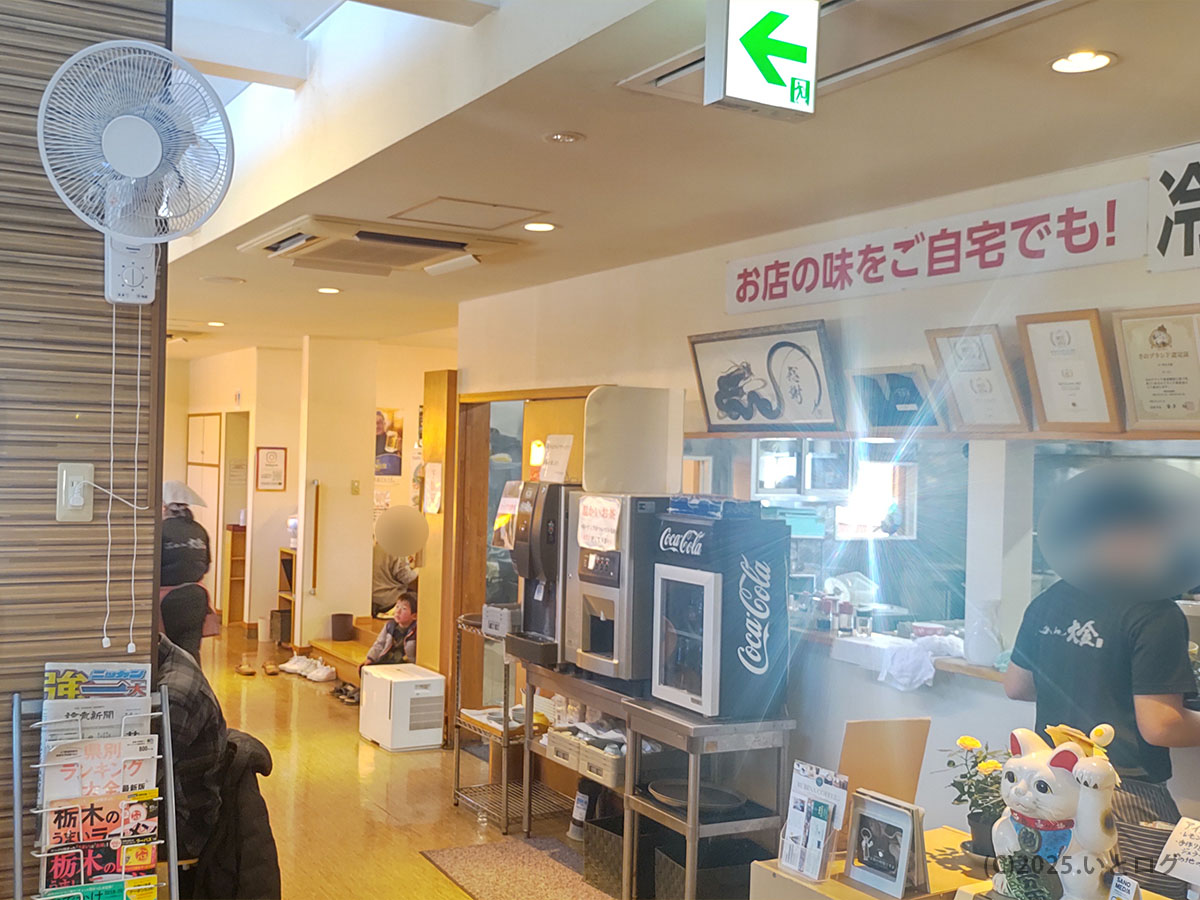らーめん大金 佐野の店内カウンター周り。メニューやテイクアウト案内が並び、お土産ラーメンも購入可