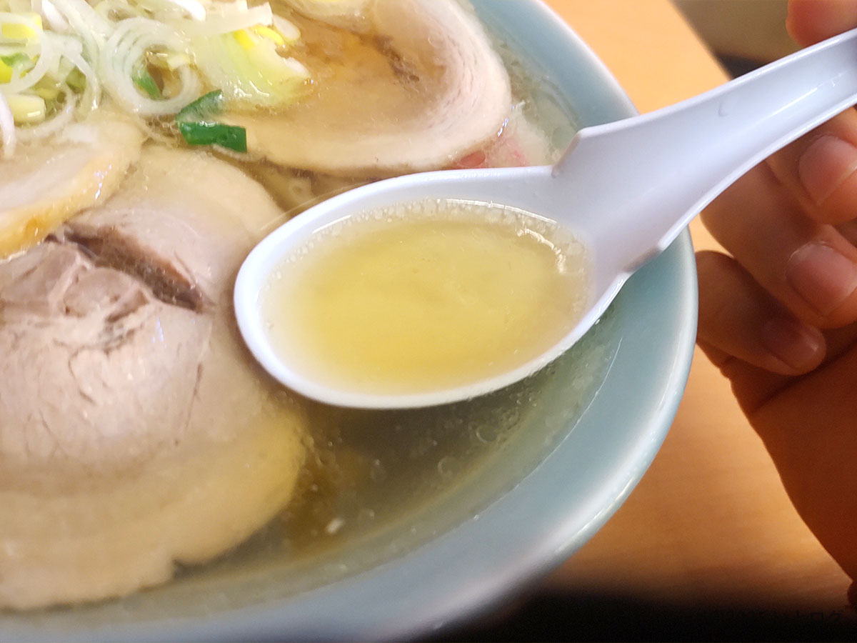 黄金色のスープをレンゲですくう瞬間。らーめん大金 佐野ラーメンのあっさりダシがキラリと輝く