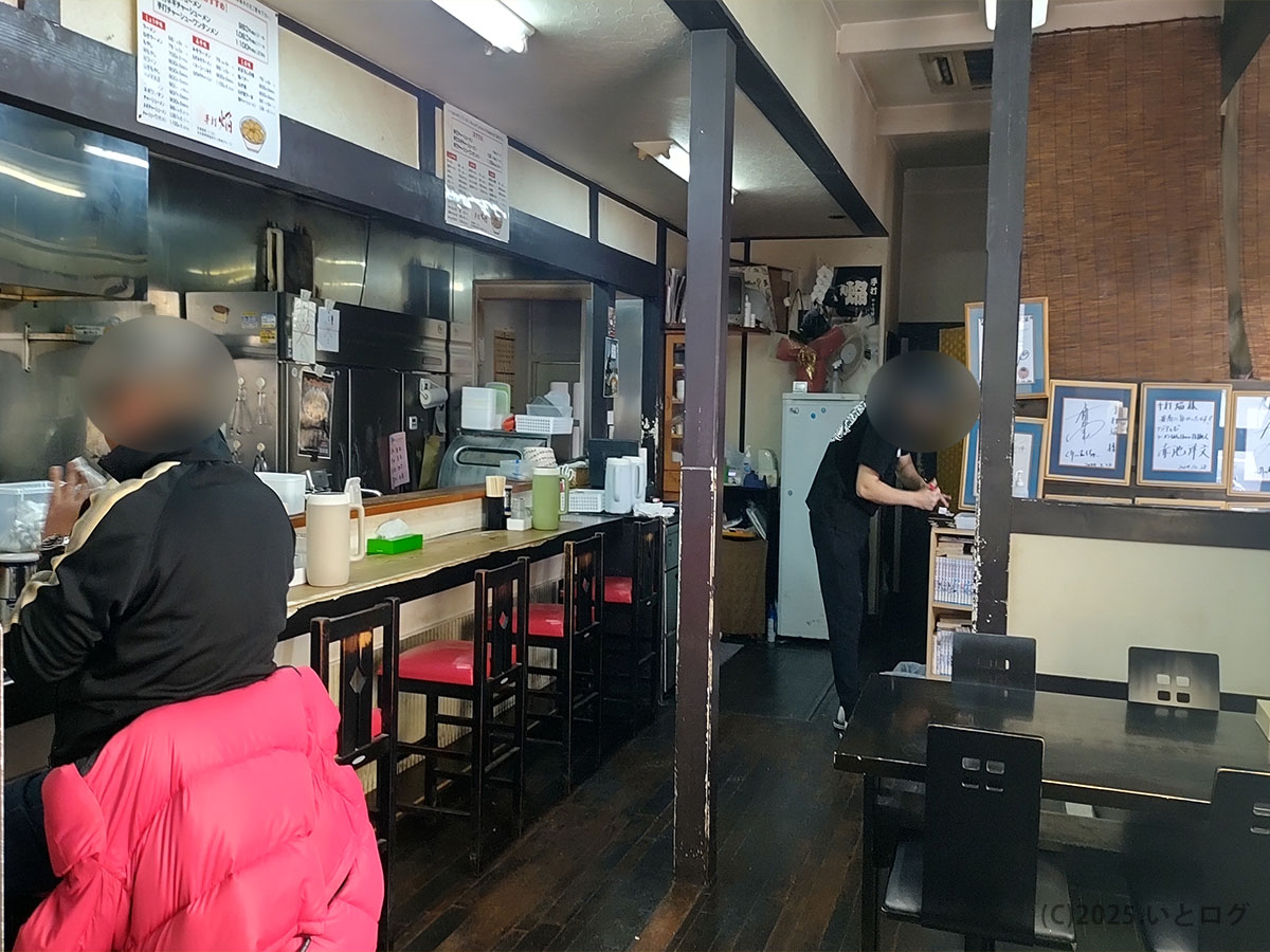木目調カウンターとサイン色紙が並ぶ手打 焔の店内風景。夜営業の落ち着いた雰囲気を切り取った一枚