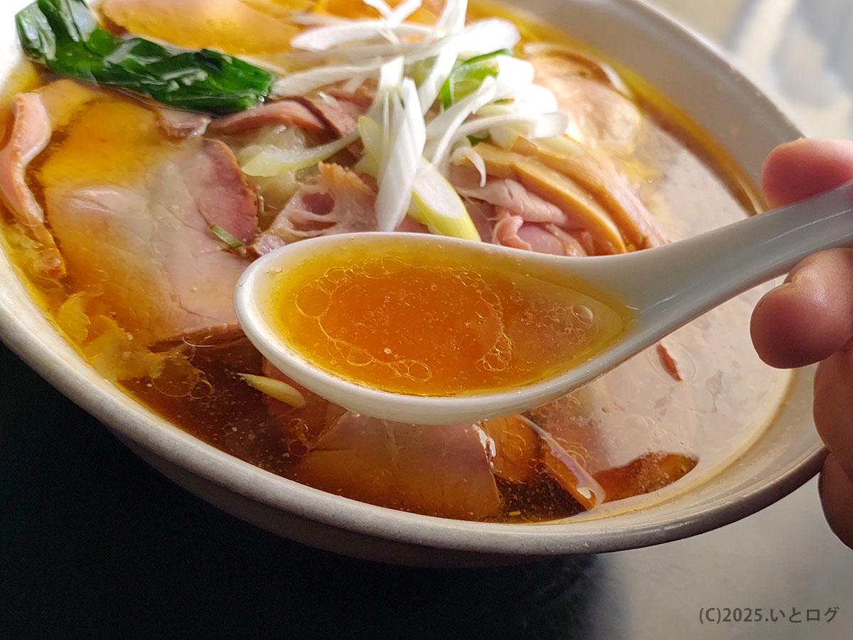 レンゲにすくった澄んだ醤油スープ。日本一級の旨味を感じる手打 焔ラーメンをクローズアップ