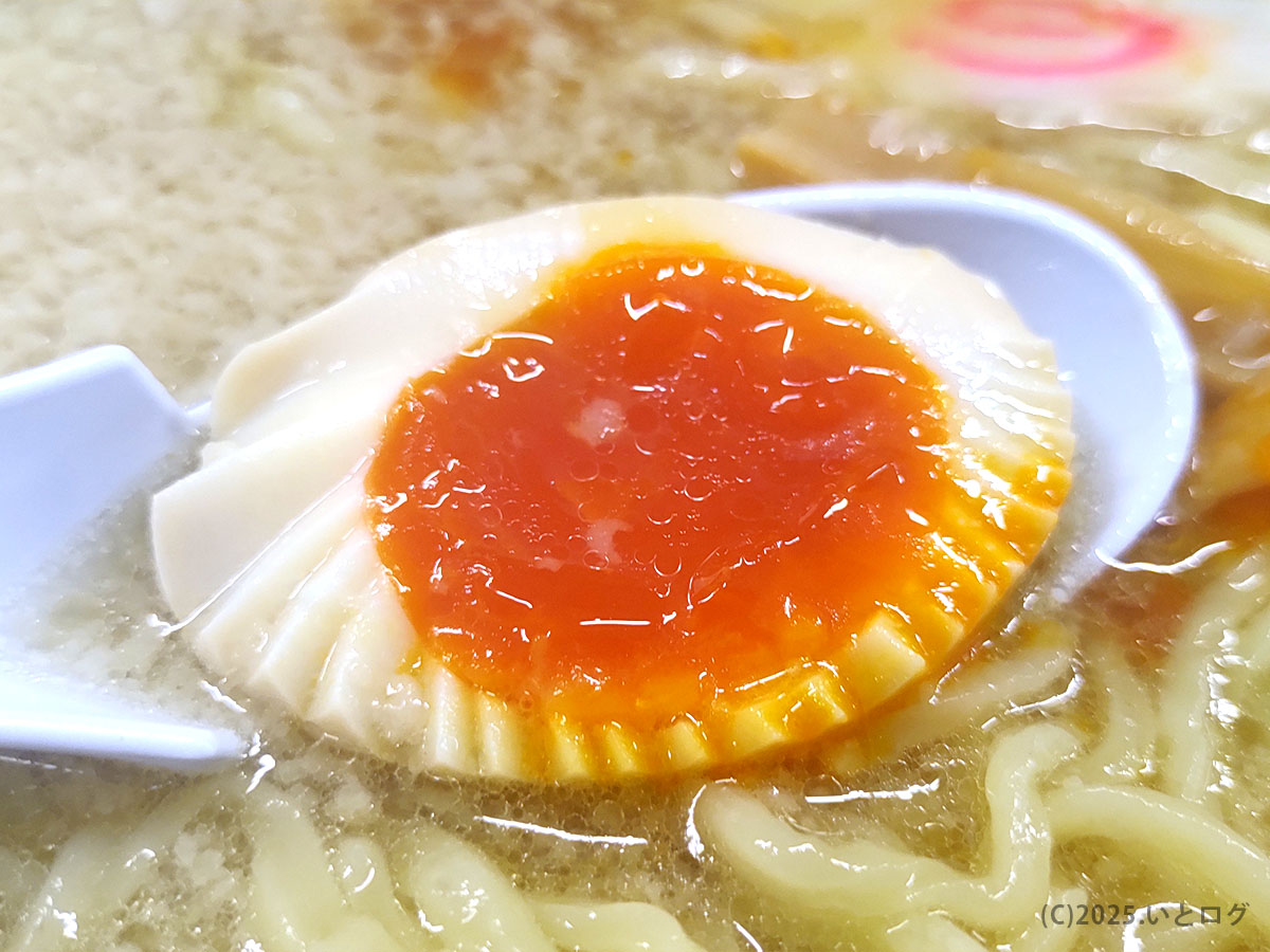 とろける半熟味玉の断面ショット。濃厚な黄身がスープに溶け込み麺と絡むシズル感。