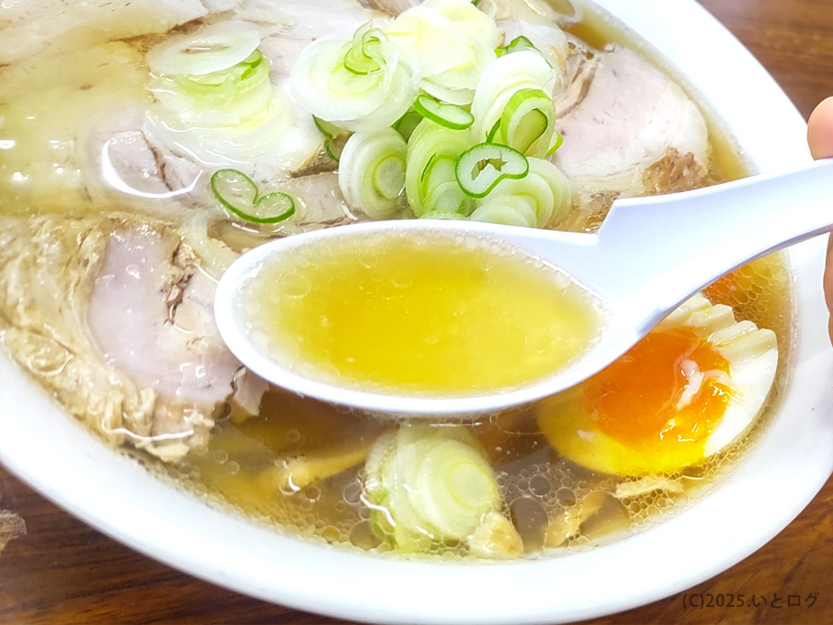 レンゲですくった日向屋 ラーメンの鶏ガラベース透明スープ。クリアなのにコク深い黄金色がキラリ