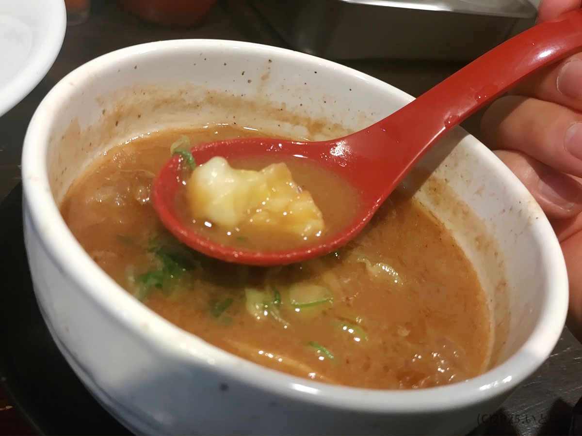 牛モツの旨みが溶け込んだ濃厚つけ汁をレンゲですくう瞬間。「製麺処 蔵木 高知」名物のコク深いスープが湯気を立てる。