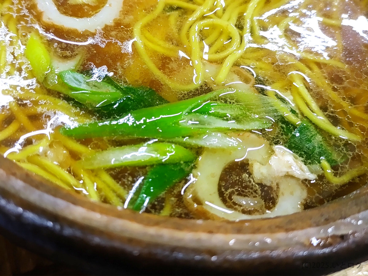 ネギとちくわが浮かぶ土鍋の表面。油膜がキラリと光る鍋焼きラーメンのラストスパート。