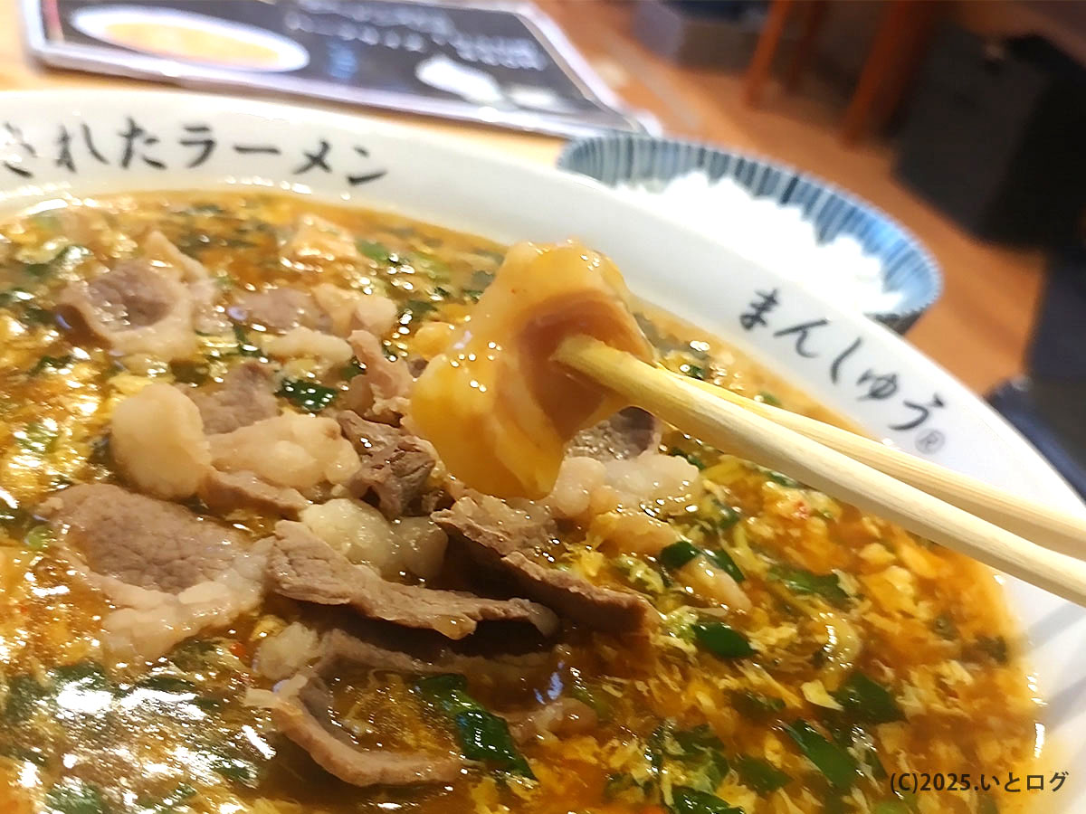 箸で持ち上げたホルモン。ピリ辛餡がまとい、ジャン麺らしいワイルドな旨みを強調