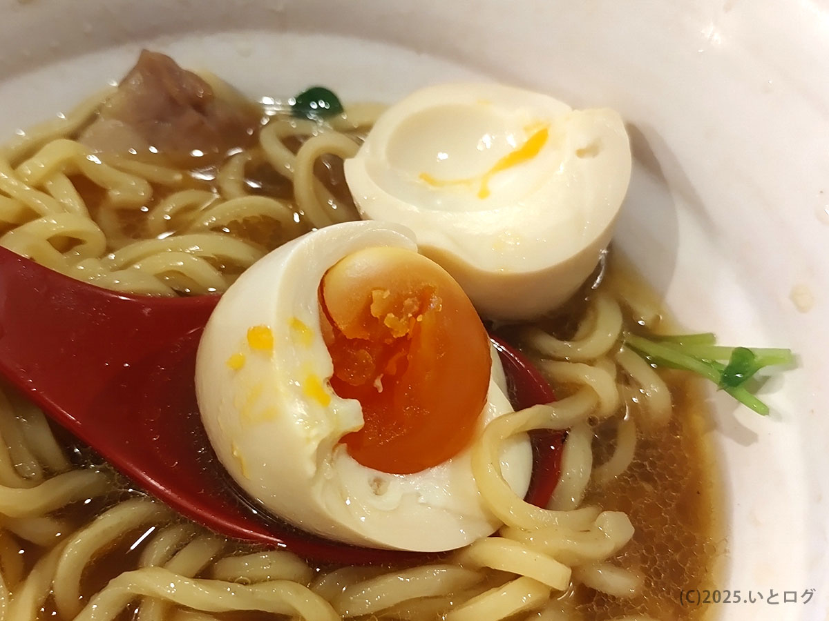 半熟味玉を割ると濃橙の黄身がとろり。スープと絡む麺にコクをプラスしているシーン。