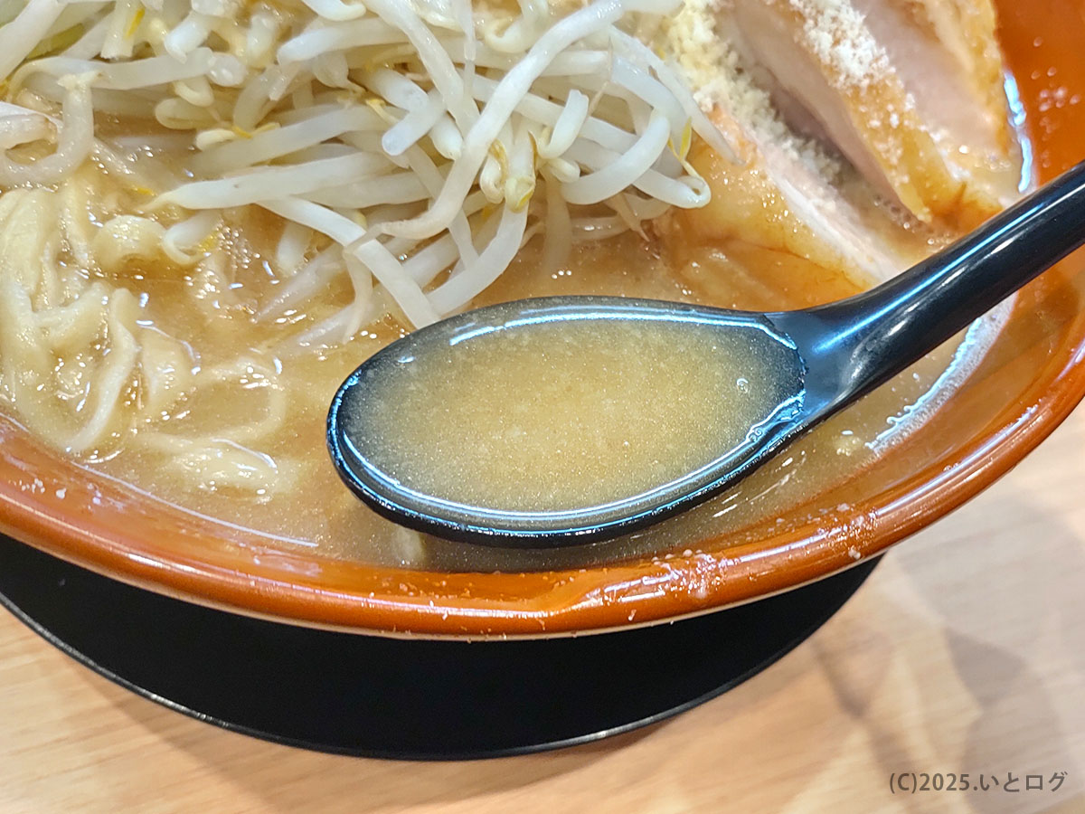 黒レンゲですくった背脂入り豚骨醤油スープのとろみと艶。検索候補「豚山 まずい」を裏切るコクの深さが伝わるクローズアップ。