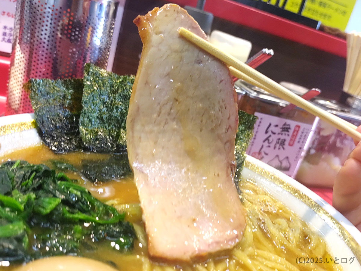 箸で持ち上げた大判チャーシュー。近江道家のビールと合わせてライスにのせたくなる、香ばしく厚みある一枚。