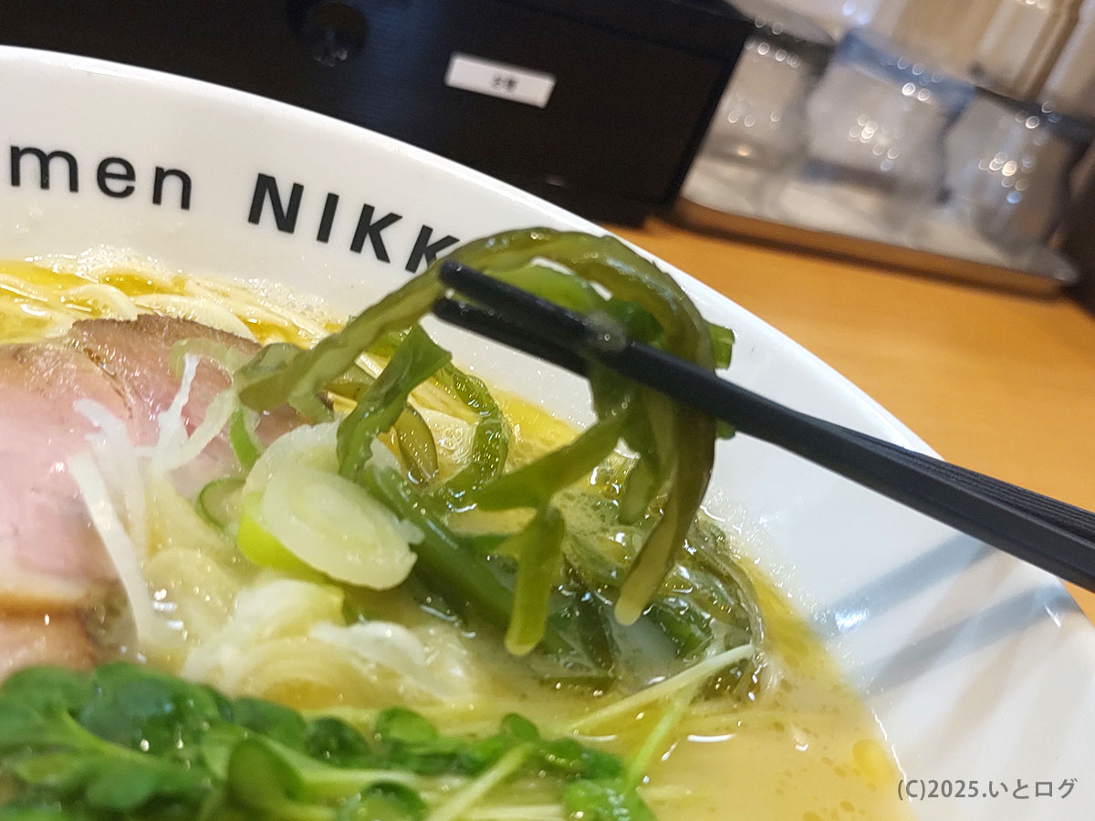 箸で持ち上げたあおさ海苔と青菜。磯の香りが鶏白湯に爽やかなアクセントを添える。