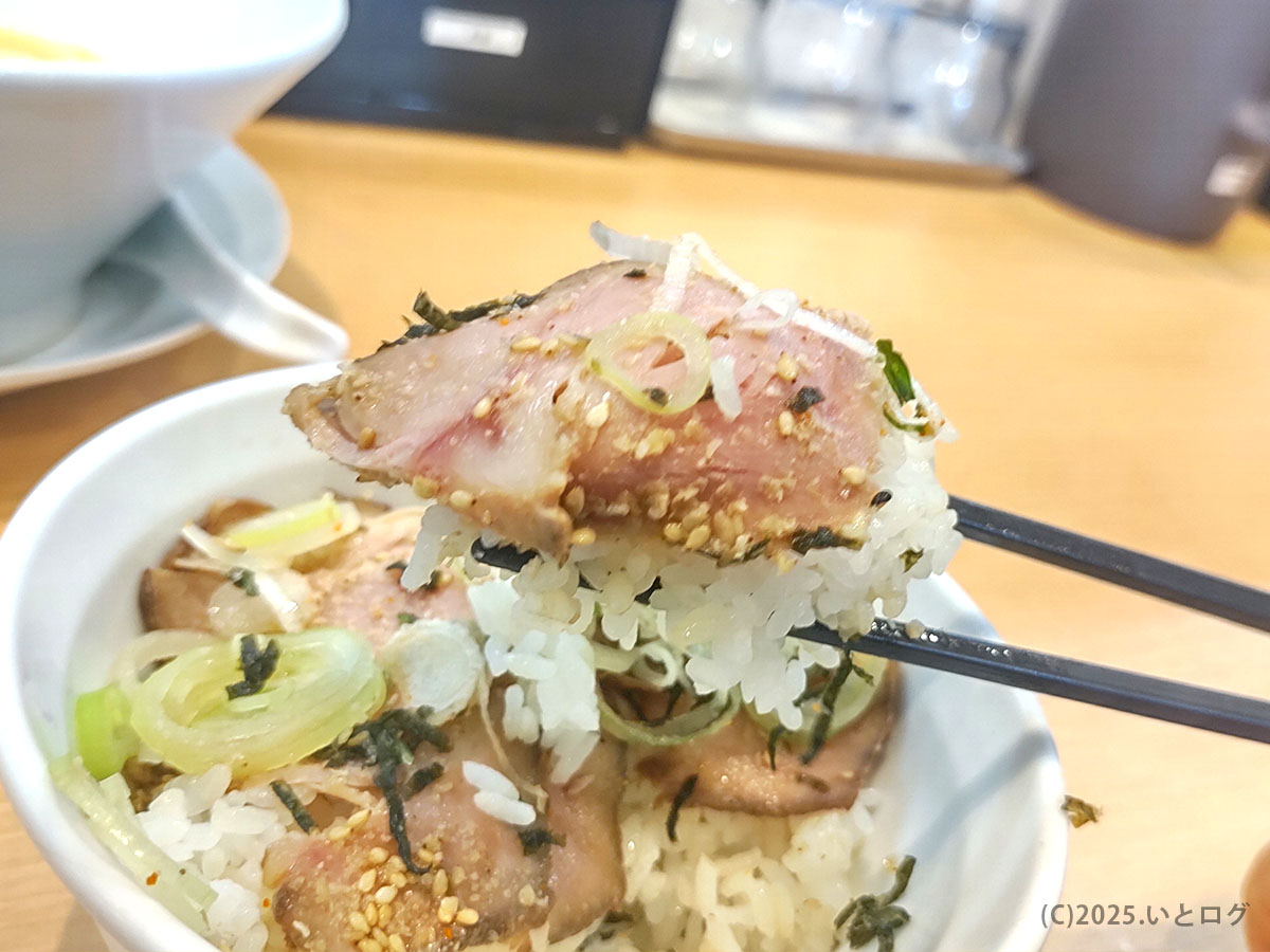 胡麻と刻み海苔が香る豚たたき飯を一口持ち上げたアップ。チャーシューのレア感と白米のハーモニーが伝わる。