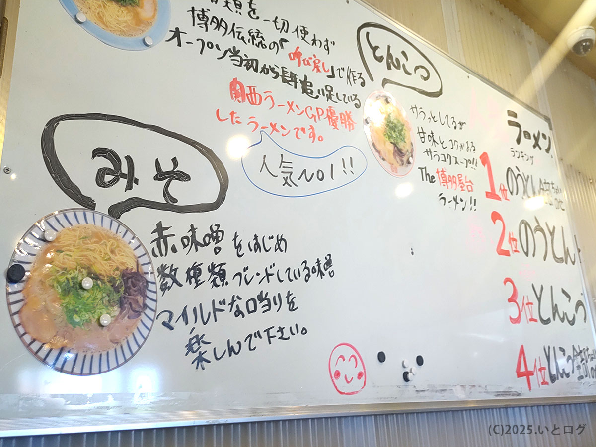 店内ホワイトボードの手書きメニュー。「みそ」「とんこつ」の説明と人気No.1案内が並ぶ／草津市 ラーメン 真咲雄