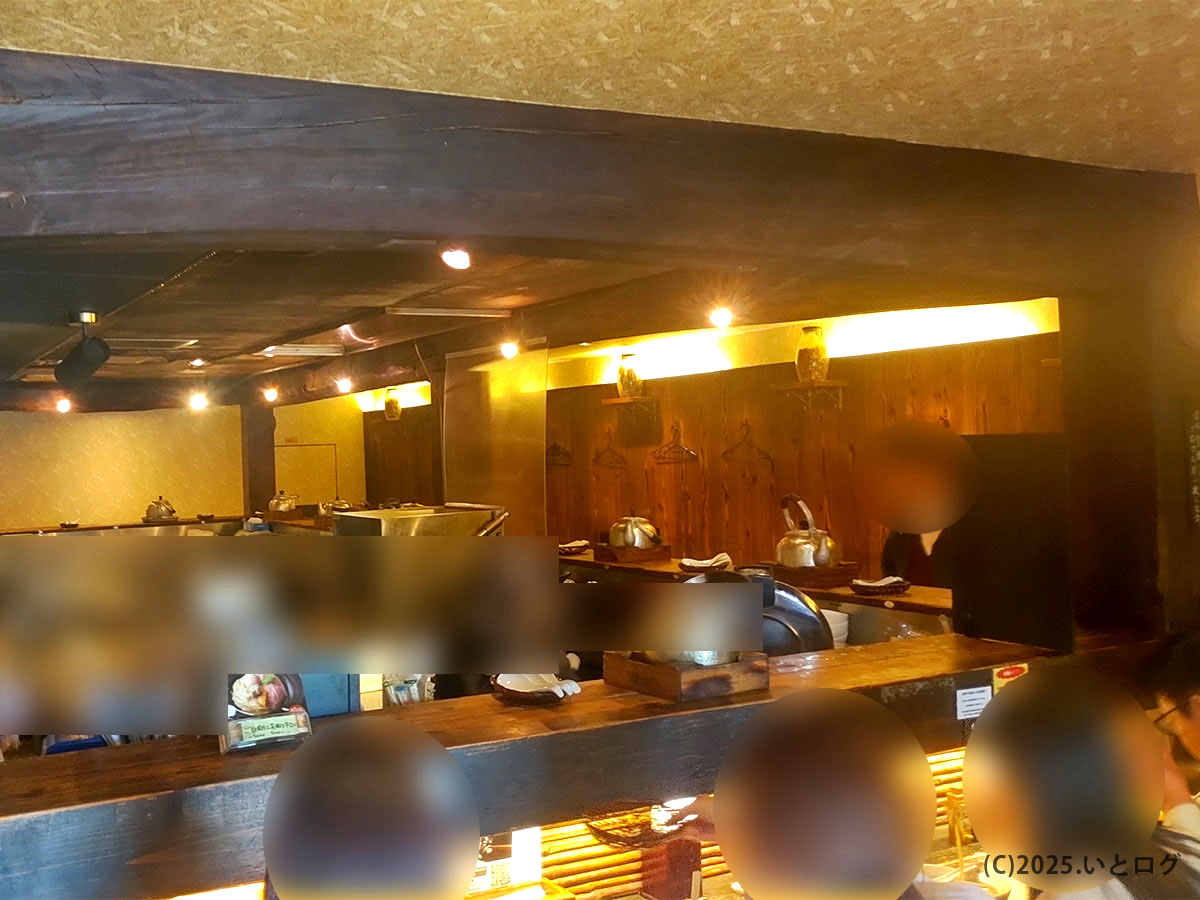 天下ご麺 滋賀・大津の店内風景。木の梁とカウンターが落ち着く、やかんが並ぶ厨房を囲むレイアウト。
