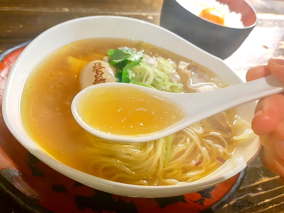 琥珀色に澄んだスープをレンゲですくう「天下ご麺 大津」の支那そば。上品な香りとやさしい旨み。※「天下ご麺 まずい」と迷う人の不安を払う一口。