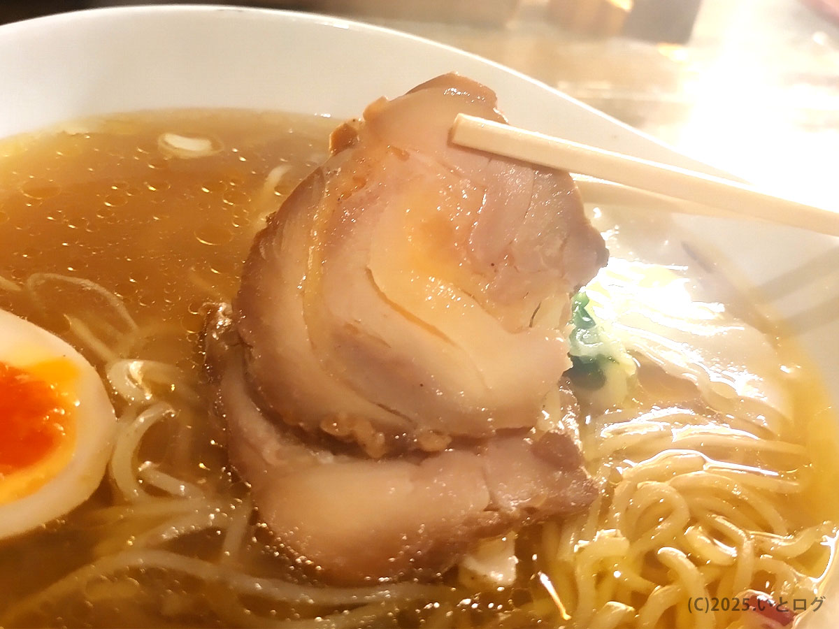 巻きバラの豚チャーシューを持ち上げたカット。ほどける脂の甘みが琥珀色のスープとよく合う、天下ご麺 大津。