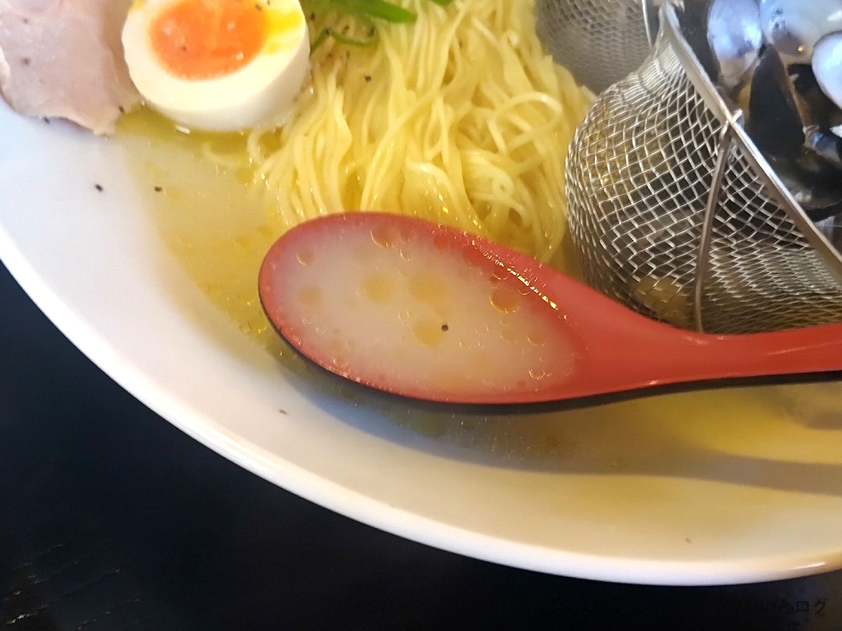 かみあり製麺 出雲のしじみ塩ラーメン。黄金色に透き通ったスープをレンゲですくった様子。しじみの旨味が広がる一口。