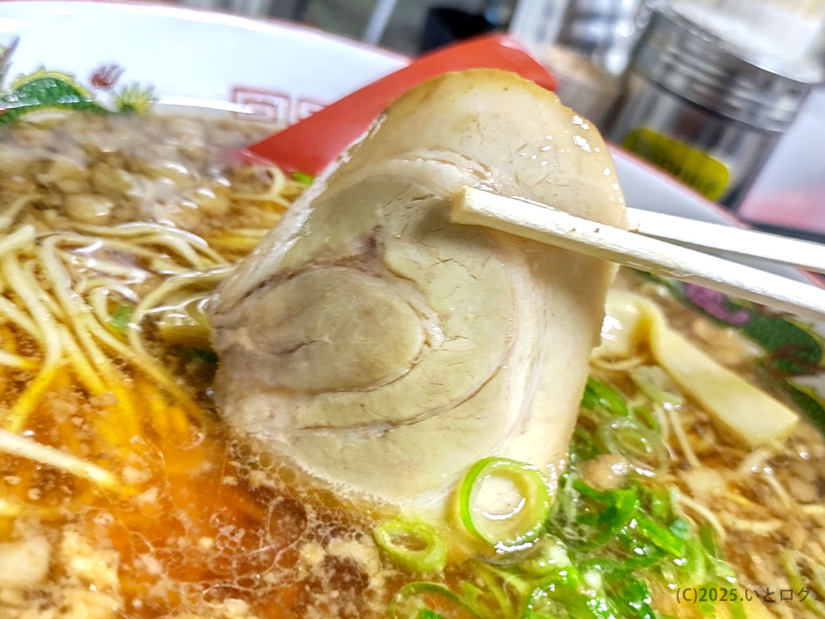 尾道ラーメン一丁のチャーシューを箸で持ち上げた様子。脂が程よくのり、口の中でほろりと崩れる。福山で長年愛される味わい。