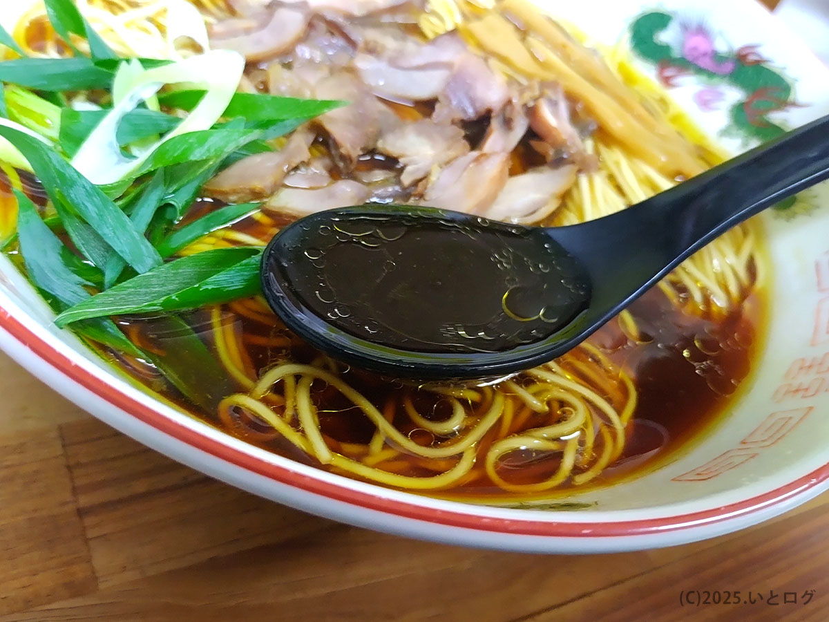 笠岡ラーメン いではらのスープをレンゲですくった様子。鶏の旨みと醤油のコクが一体となり、香ばしい風味が広がる。笠岡市を代表する中華そばの深い味わい。