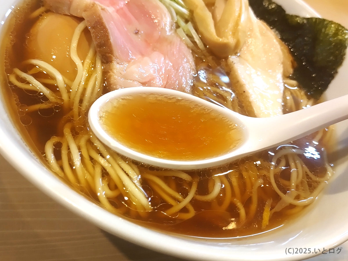 レンゲにすくった琥珀色のスープの質感がわかる寄り。繊細な油膜が美しい―麺屋 鶯 uguisu レビュー