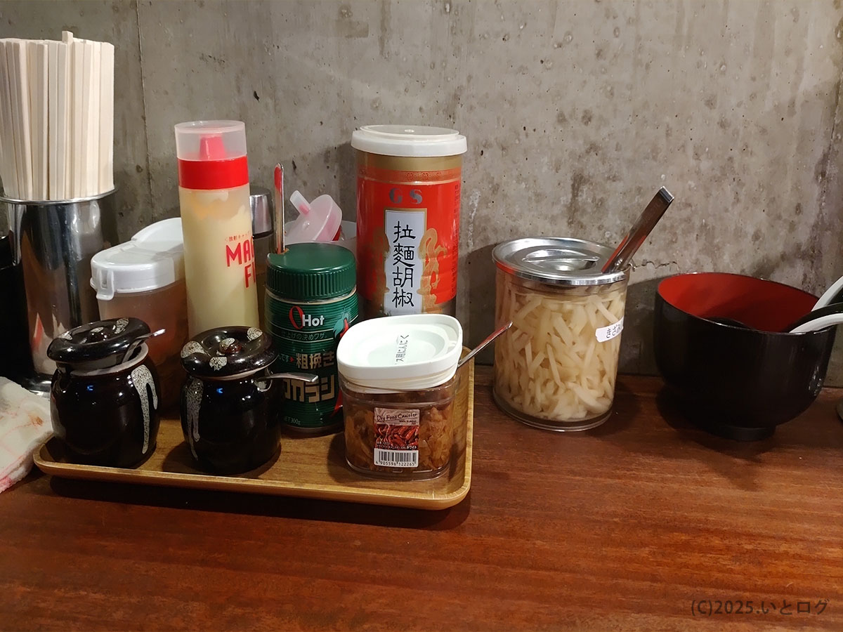 家系ラーメン クックらの卓上調味料。刻みしょうが、にんにく、豆板醤などが並び、味変の自由度が高い。