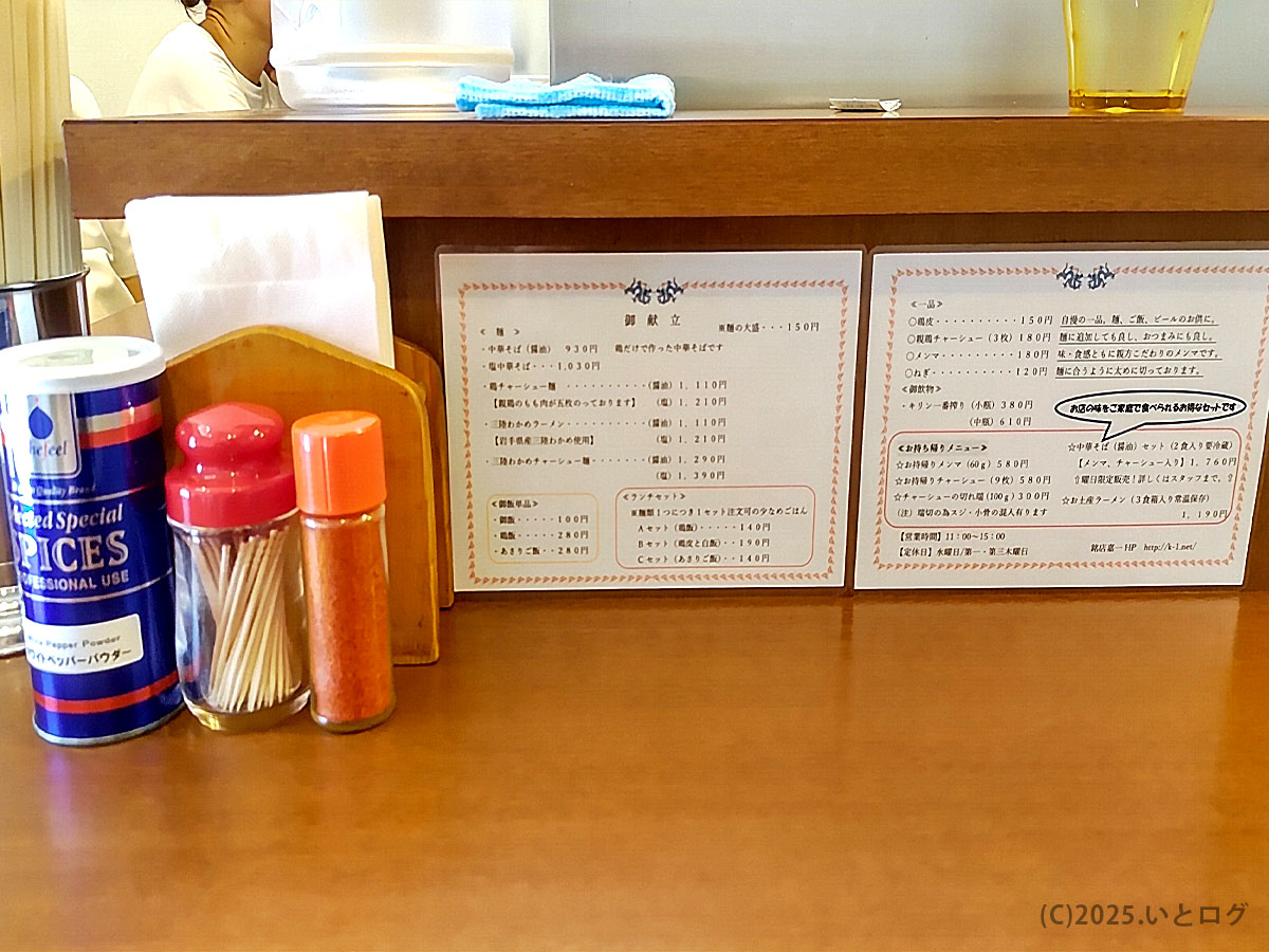 仙台の中華そば 嘉一 国分町店のカウンター。ホワイトペッパーや七味とともに、定番メニュー「中華そば(塩・醤油)」の案内が掲示されている。嘉一ラーメンの基本を伝える一枚。
