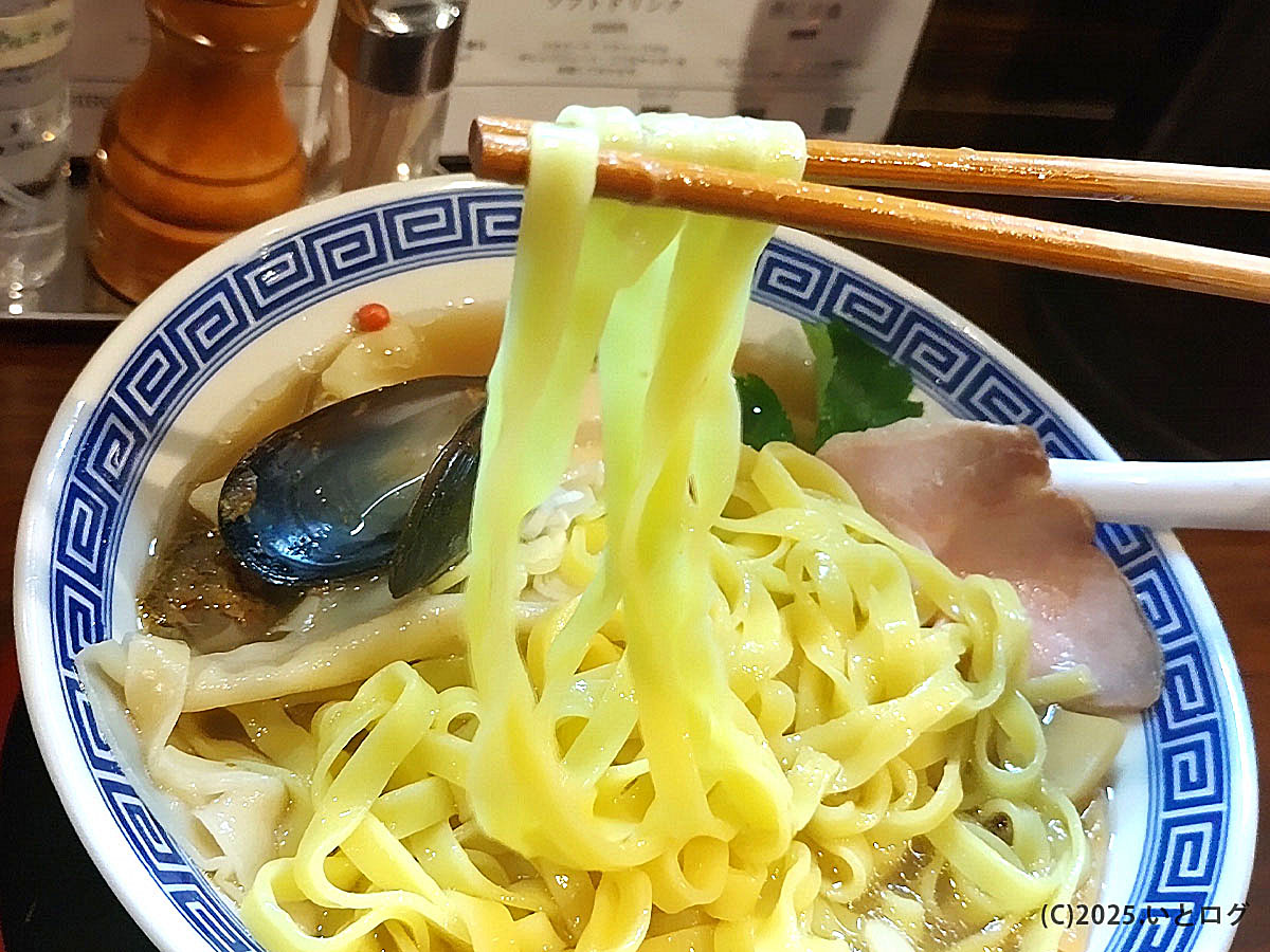 だし廊 仙台南町通り本店『貝だし塩そば』の麺リフト。平打ちの中太麺が黄金色のスープをしっかりと絡め取る。