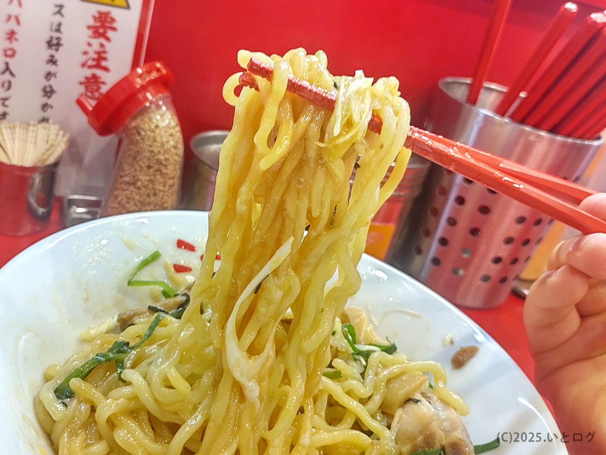 麺リフトで湯気まで写るあつあつ油そば。真っ赤なカウンターと赤い箸が映える東京麺珍亭本舗 甲府南店の実食シーン。