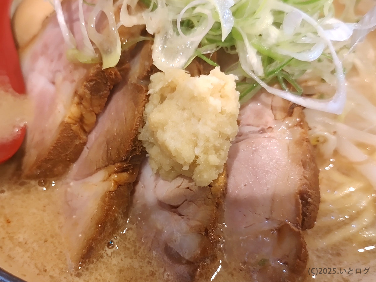 厚切りチャーシューの上におろし生姜を添えたアップ。クチコミで評判のコク深い組み合わせが伝わる。