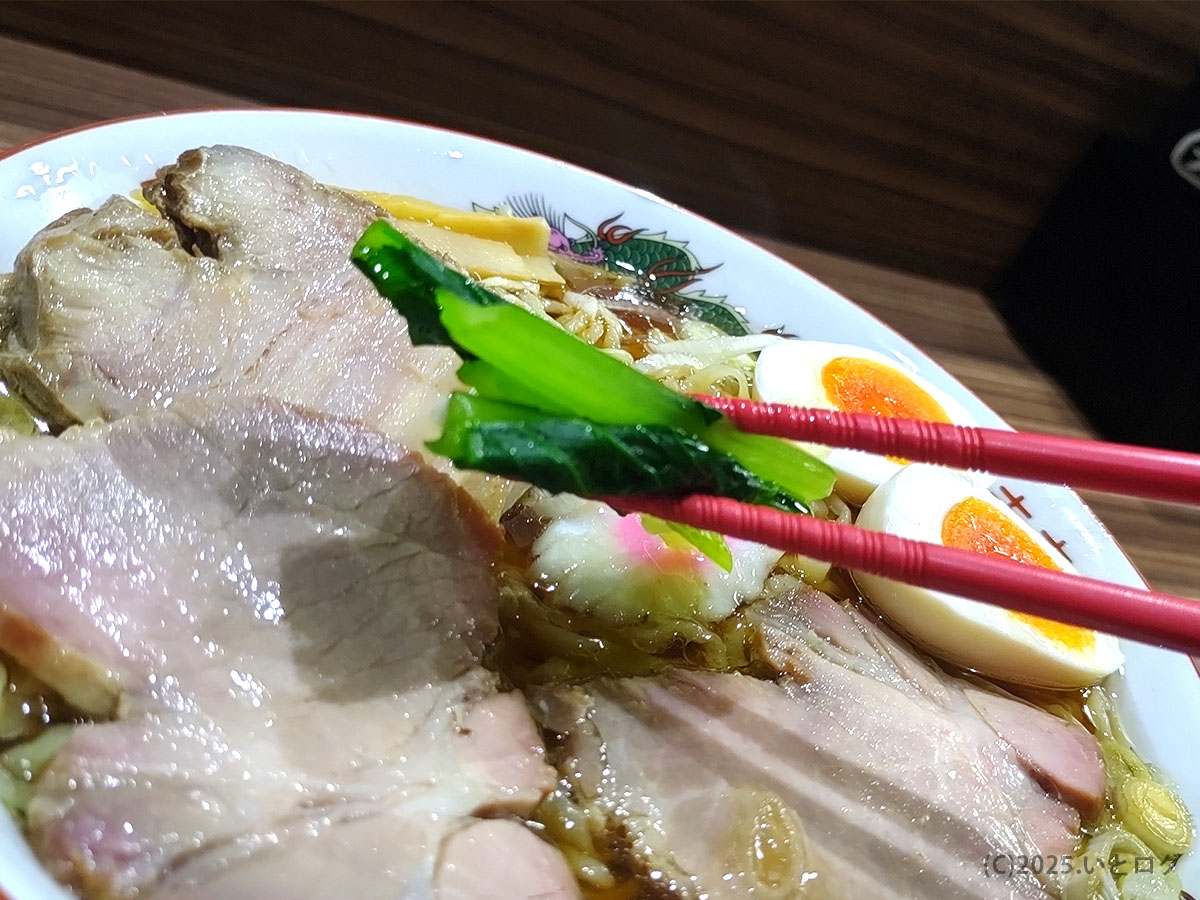 鮮やかな青菜を箸でリフトした彩りショット。中華そば じんない レビューで伝えたい野菜の清涼感。