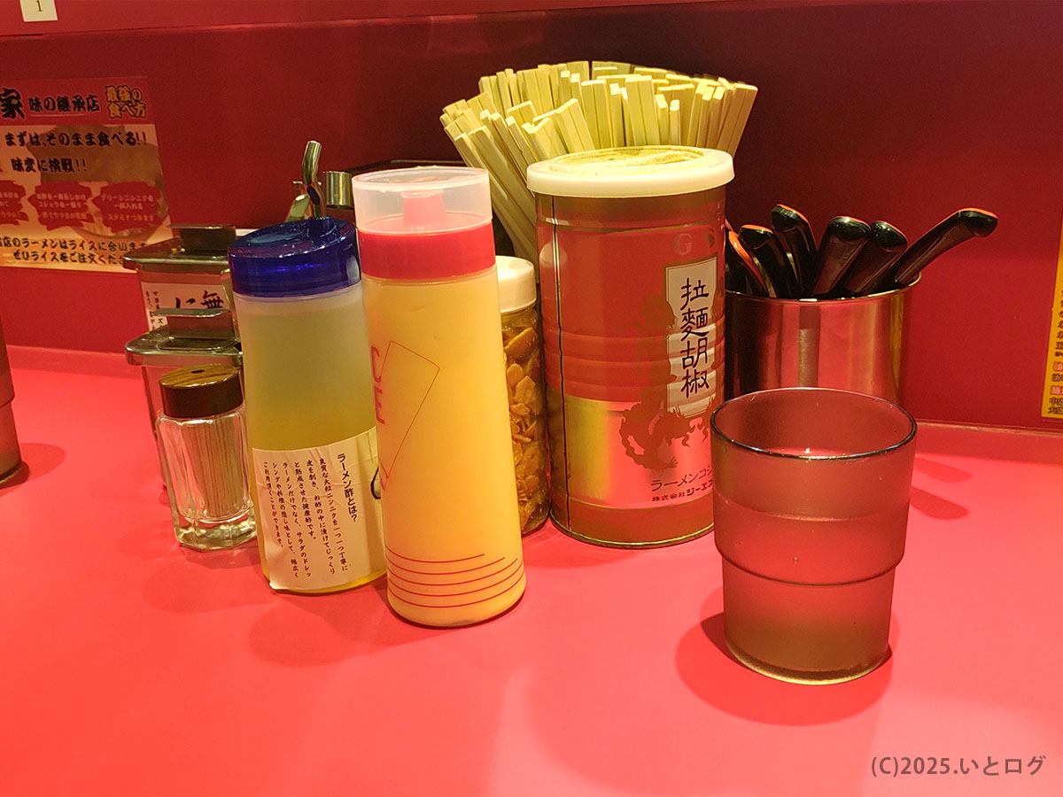 カズ家 大森店の卓上装備。すりごま、刻みしょうが、ニンニクなど家系ラーメンの味変に欠かせない調味料が並び、王道家系のスタイルを踏襲している。