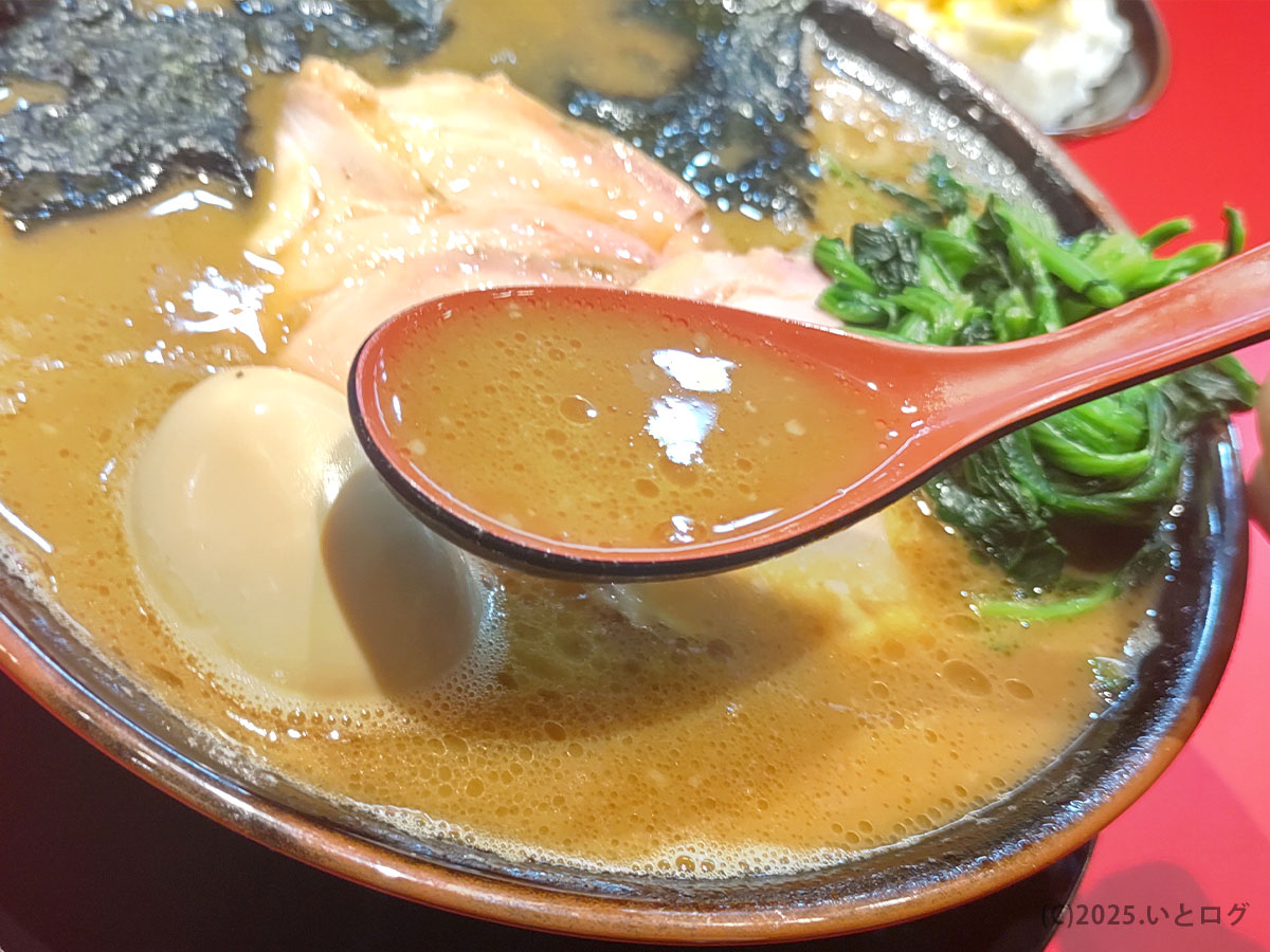 カズ家 大森店の豚骨醤油スープをレンゲですくった様子。濃厚で香り豊かな口当たりが特徴で、カズ家 ラーメンの魅力を象徴する一杯。