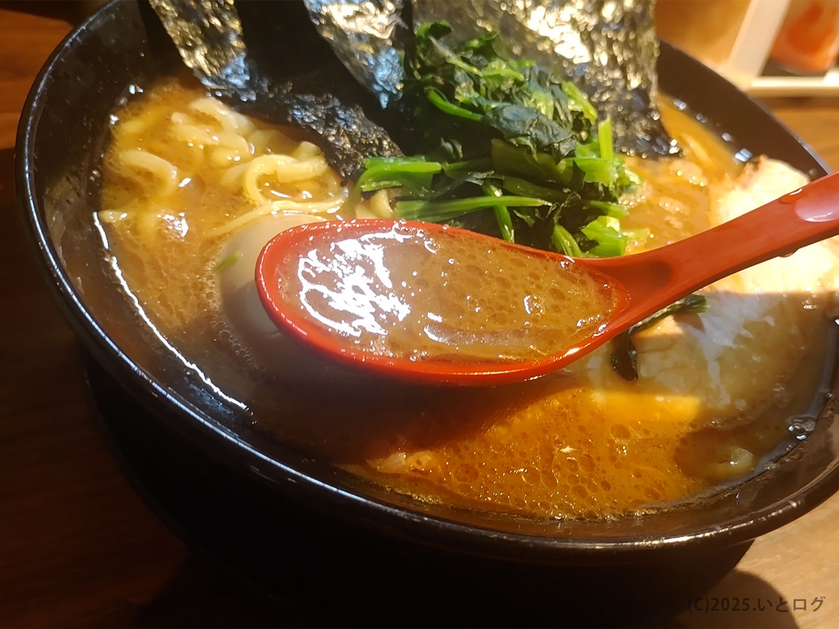 輝道家 水道橋店の濃厚豚骨醤油スープをレンゲですくった様子。直系家系らしい旨味の強さが感じられる一杯。