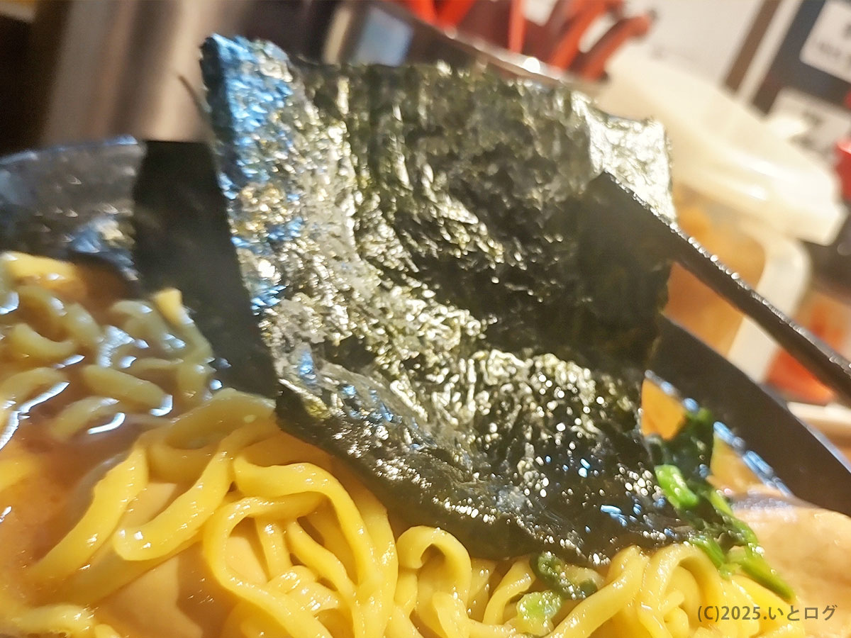 輝道家 水道橋店の高級海苔を箸で持ち上げた写真。家系の定番トッピングで、スープとの相性が良い。