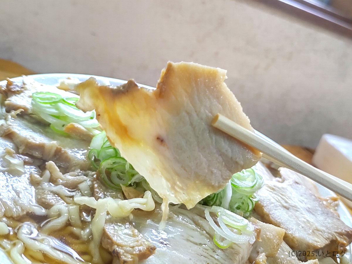 肉厚チャーシューを箸で持ち上げた様子。富山県上市町の中華そば あざみに名物の肉中華で、醤油ダレが染みた一枚肉が柔らかい。