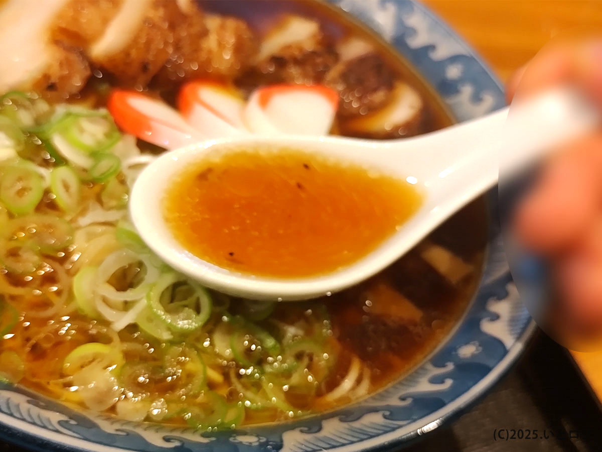 大石家 塩尻店の醤油スープをレンゲですくった様子。動物系の旨みと香ばしい香りが特徴で、大石家ラーメンらしい透明感のある茶色いスープがよくわかる。
