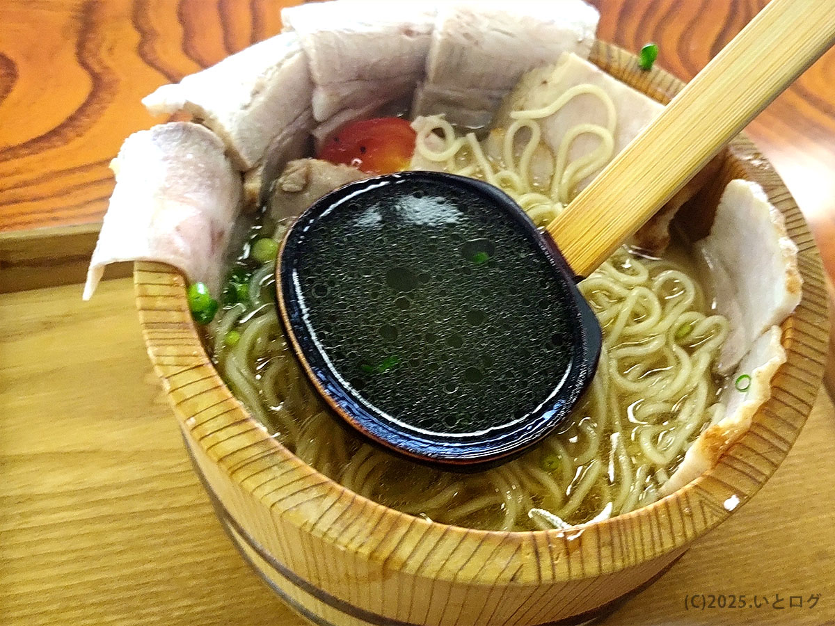 レンゲで透き通るスープをすくうなんぶの湯オリジナルラーメン、木桶ならではの香り