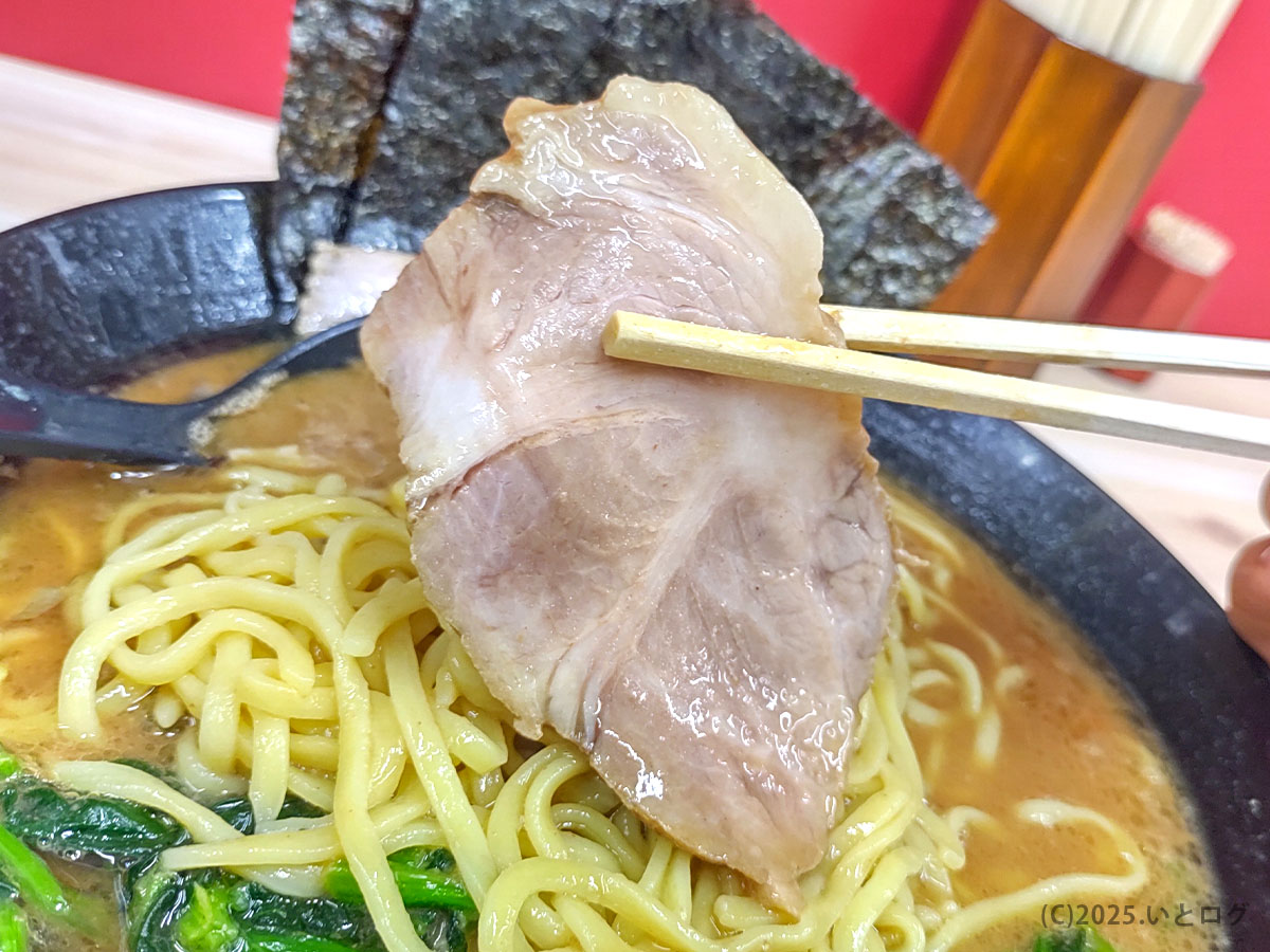 武道家 口(くにがまえ)国分寺のチャーシューを箸で持ち上げたアップ。武道家系らしい肉厚の仕上がりで、濃いめスープと相性抜群。国分寺で人気の武道家系列を象徴する具材。